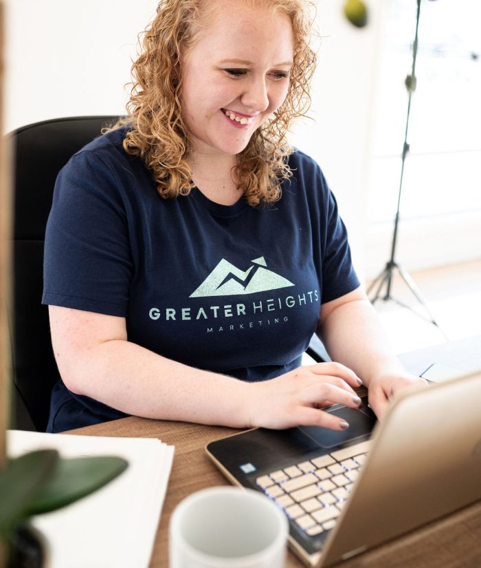 Hailey Fackrell getting web design and branding work done and smiling at computer